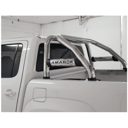 White pickup truck in a garage with a chrome tubular roll bar and an Amarok badge in the bed area