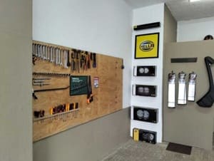 Tool display area with a pegboard wall holding hand tools and a STIHL-branded shelf unit with tools and gas cans on display.